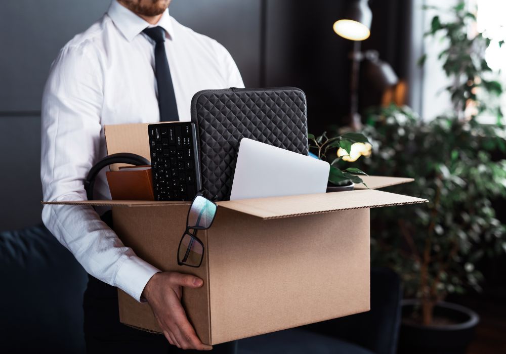 A person carrying a box of their belongings after being dismissed during the probation period