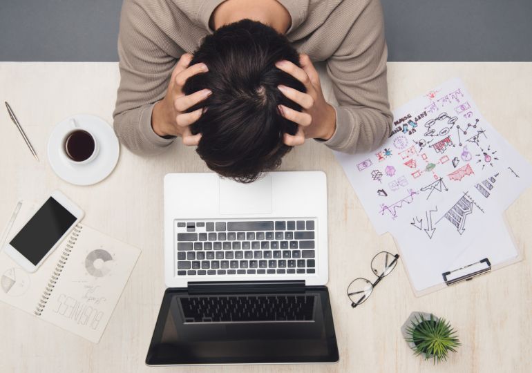 A person with their head in their hands due to being stressed in the workplace