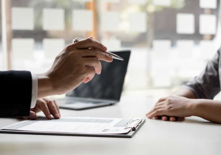 Two people signing a contract looking at new hours