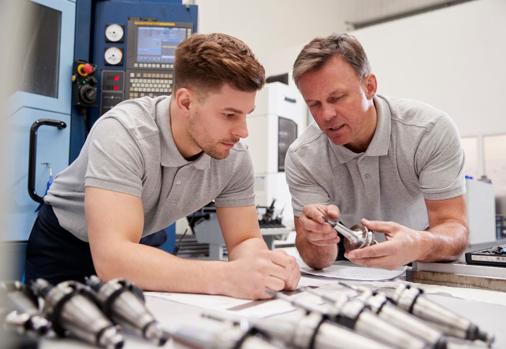 An apprentice being shown how parts fit together by a teacher