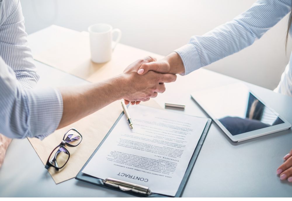 Two people shaking hands over a new job contract