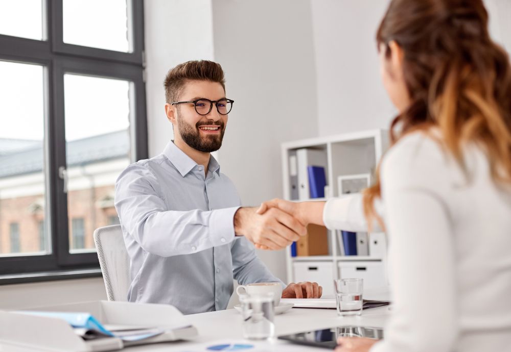 two people shaking hands at the start of a job interview