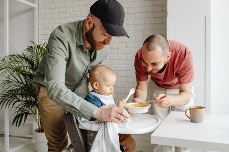 Same sex couple feeding baby in highchair