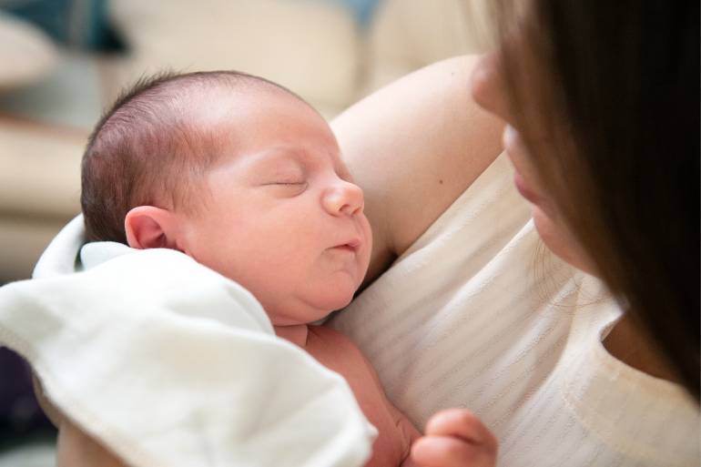 Parent on paternity leave holding their newborn baby