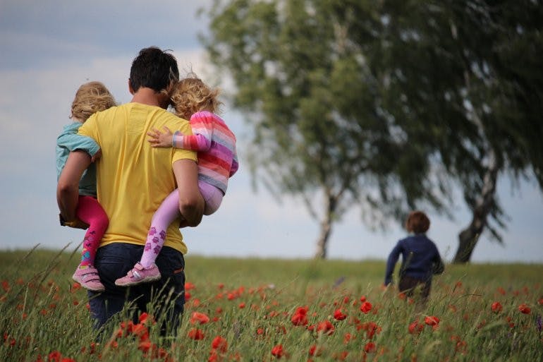father holding two children in a flower field