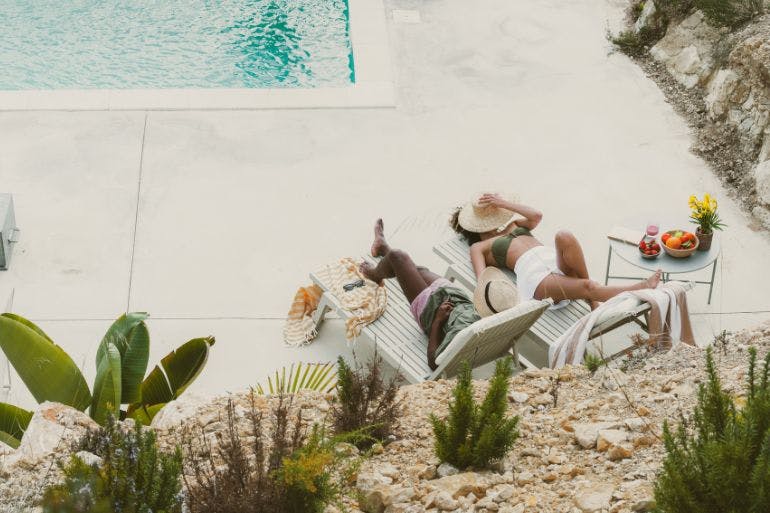 Couple sunbathing by pool on holiday