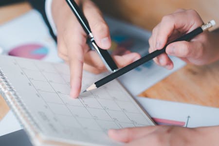 Planning employee holiday entitlement Employer and employee planning out annual leave on a calendar