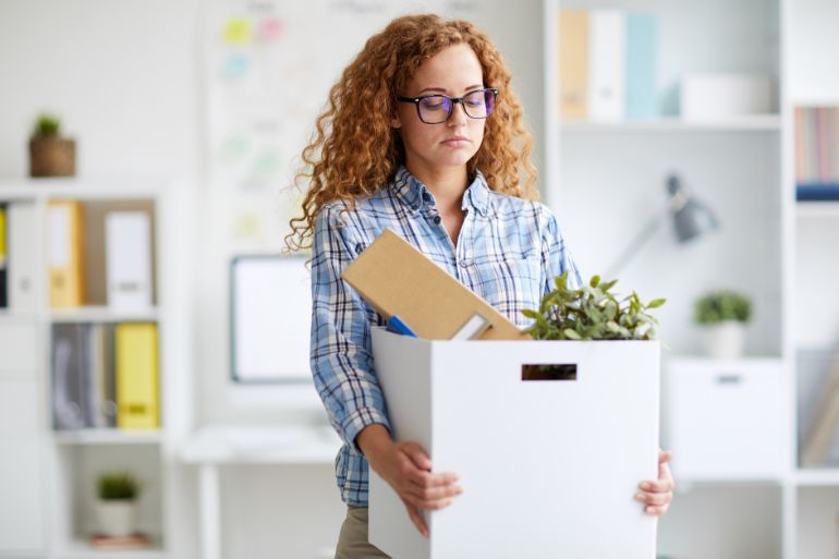 female employee leaving job with box of belongings