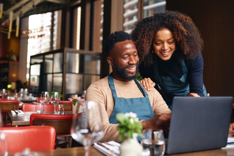 small business owners researching the cost of HR software on laptop