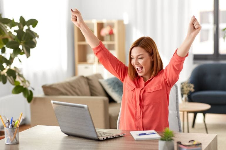 Female business owner excited seeing the benfits of HR software on laptop