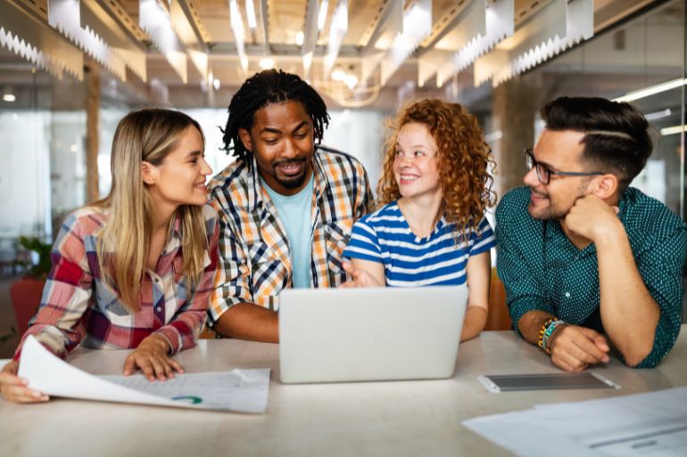 happy employees around a computer engaged in work