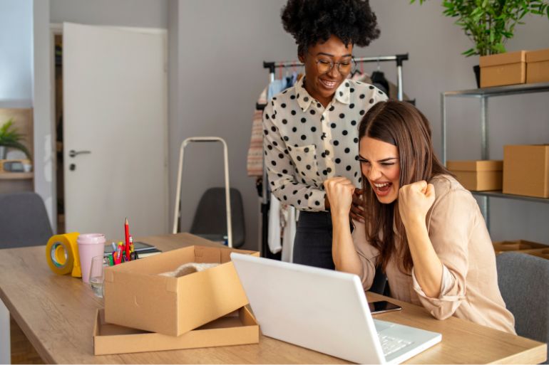 small business owner helping employee on laptop