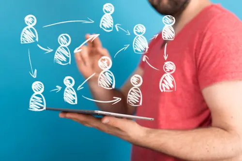 man holds a tablet displaying a employee network diagram, representing connections and relationships. Relevant to HRIS.
