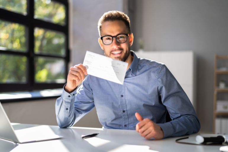 Man with glasses holding a payslip