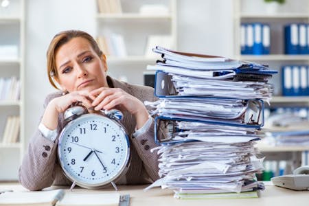 What is HR software Business owner holding a clock, with a stack of papers, wishing she had HR software.