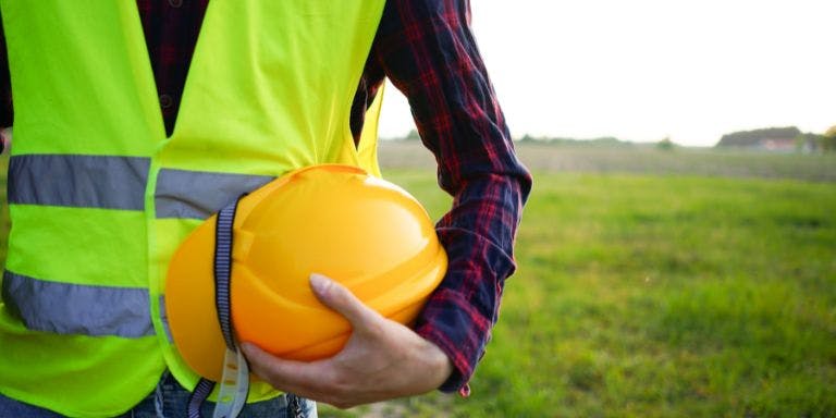 Health and Safety Person in a field with high visibility vest and hard hat