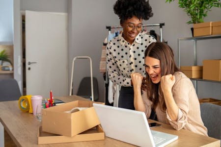 Two business owners collaborating on a laptop in an office setting, utilizing essential payroll software features.