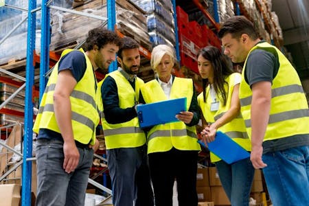 Rota planning A team of workers in a warehouse, discussing rota planning strategies.