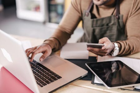 small business payroll software A small business owner utilising payroll software, on laptop, mobile phone and smart tablet.
