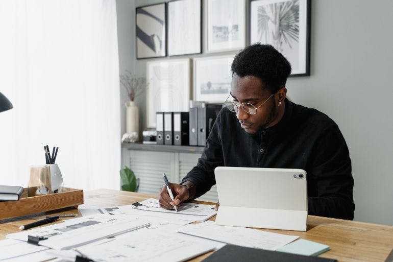 In-House vs Outsourcing Payroll Man at desk with laptop, working on payroll.