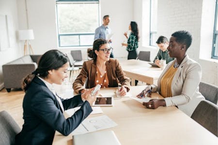 Business professionals in office meeting discussing payroll inhouse or outsourcing.