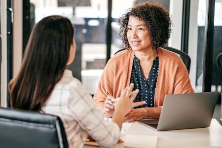 The Ontario Employment Standards Act Two women engaged in conversation at a table, related to Ontario Employment Standards Act.