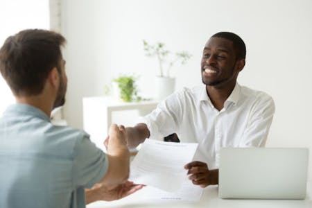 The Ontario Employment Standards Act Two men shaking hands at a desk, symbolizing agreement under Ontario Employment Standards Act.