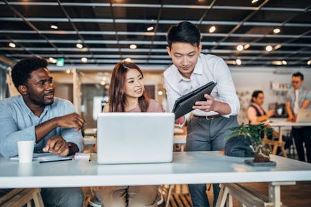 HR technology Three business owners in an office setting, examining HR technology.