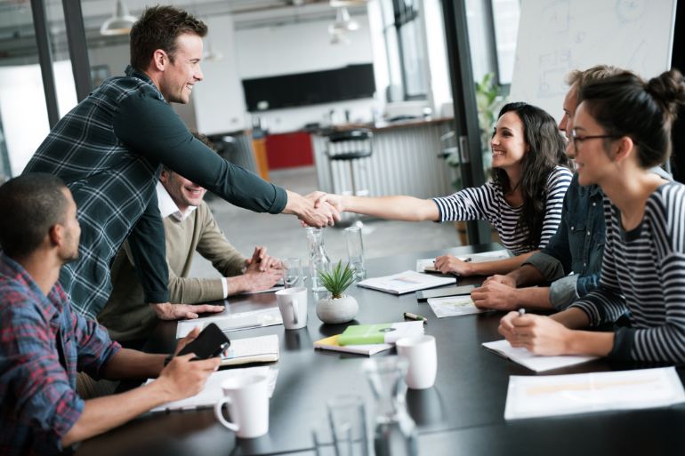 Employee and employer shaking hands at a onboarding meeting.