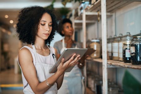 HR apps Female business owner using an HR app in her tea shop on a tablet.