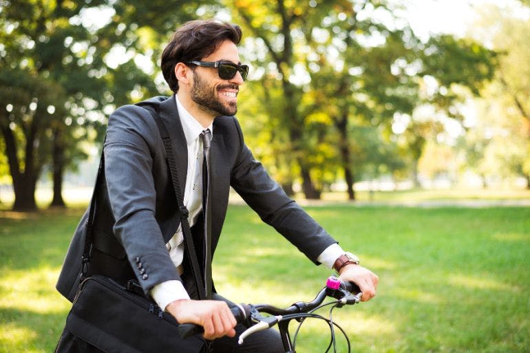 Man on a bike leaving working, happy he can disconnect from work.