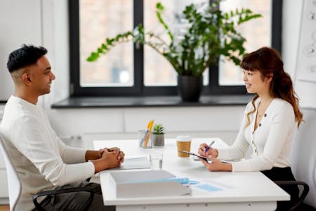 Cashing out annual leave Male employee and female employer sitting at a table in an office, discussing cashing out annual leave.