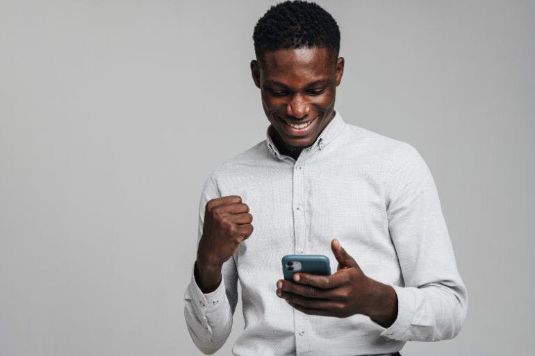 HR App Male business owner happily holding phone, engaging with HR app.