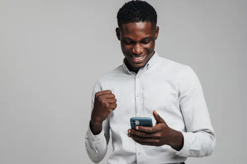 Male business owner happily holding phone, engaging with HR app.
