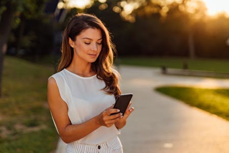 HR apps Female business owner on a walk in the park using an HR app on her phone.