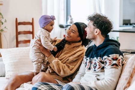 Shared parental leave A couple and their baby on couch on shared parental leave