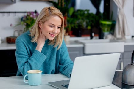 Remote onboarding A woman sitting at a table with a laptop, participating in remote onboarding.