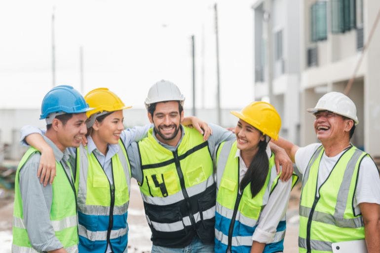 A group of construction workers smiling and laughing while prioritising staff safety.