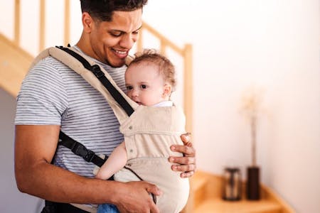 Leave at work Male employee on paternity leave at home with baby in a carrier.