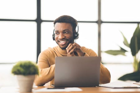 Payroll services Man with headphones smiles at his desk providing payroll services.