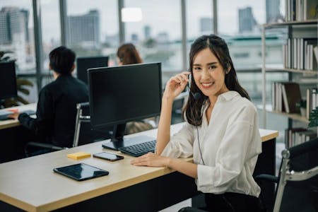 Payroll services Payroll service employee smiling at her desk in an office.