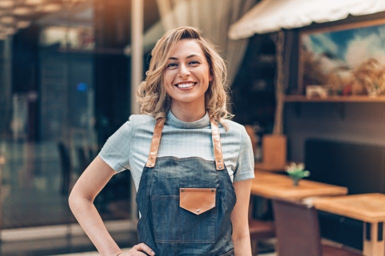 Female small business owner standing outside her cafe.
