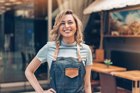Is a payroll accountant needed for small businesses Female small business owner standing outside her cafe.
