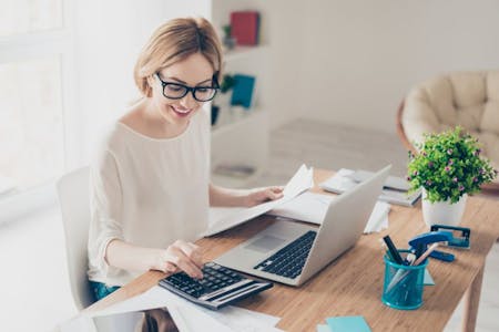 Payroll deductions Female business owner with glasses typing on laptop, handling payroll deductions.