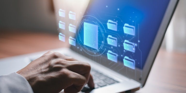Man working on a laptop displaying a folder icon, symbolising online document storage and digital organisation.