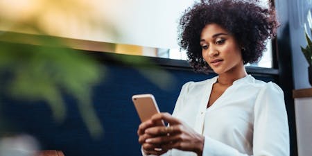 staff clocking in app Woman with curly hair checks her phone, using a staff clocking in app .