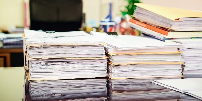 Stacks of paper documents on a desk.
