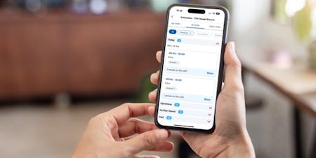 Scheduling app Hands holding a phone showcasing the BrightHR app for scheduling employees.