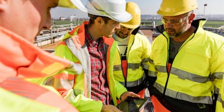 Risk assessment steps group of construction workers examining a document related to the stages of a risk assessment on-site.