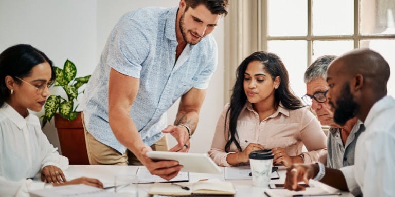 Employer discussing rotating rosters with employees in a meeting at a table.